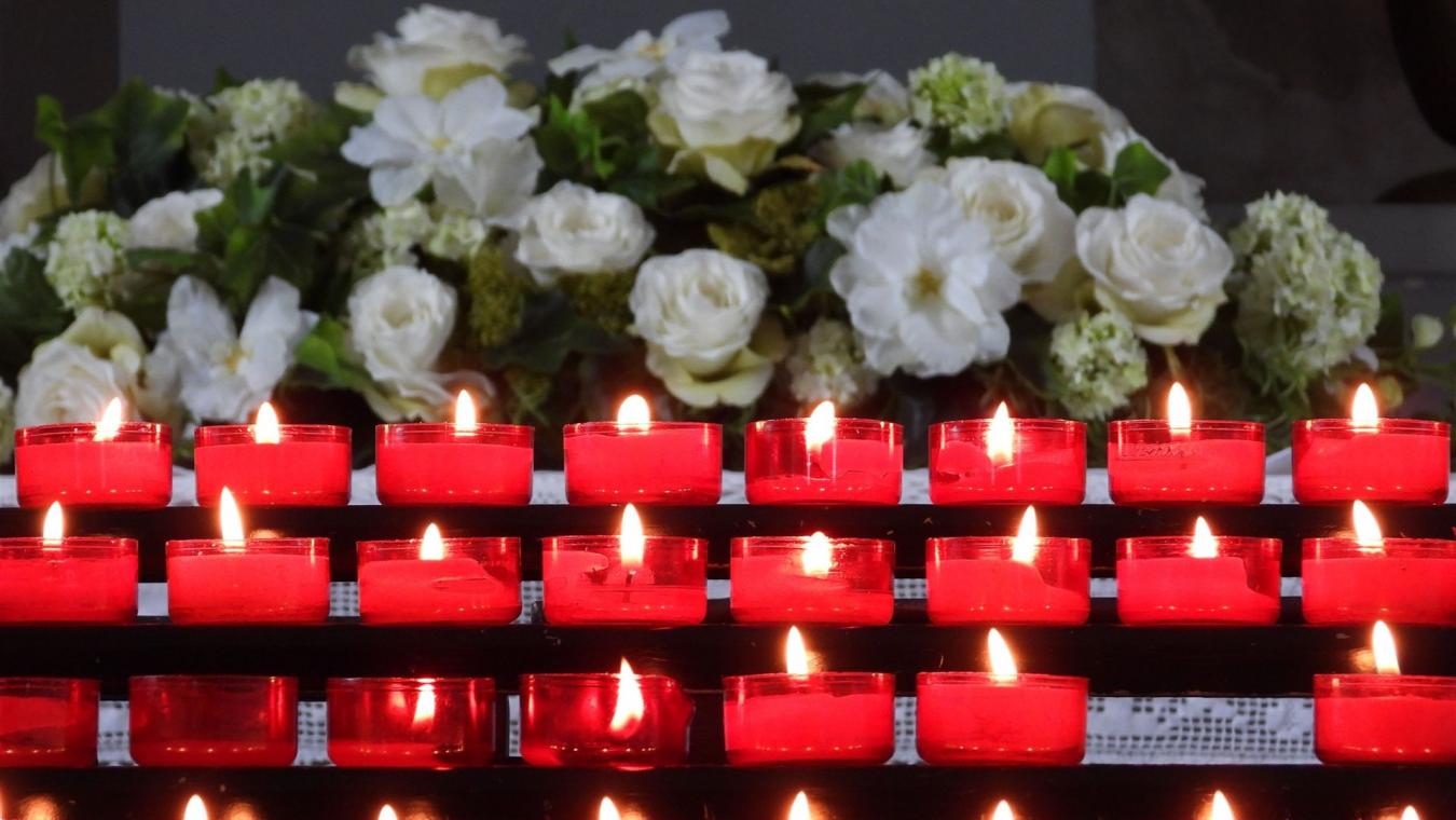 Ein ruhiges Arrangement aus brennenden roten Kerzen mit weißen Blumen im Hintergrund, das eine friedvolle Atmosphäre schafft.